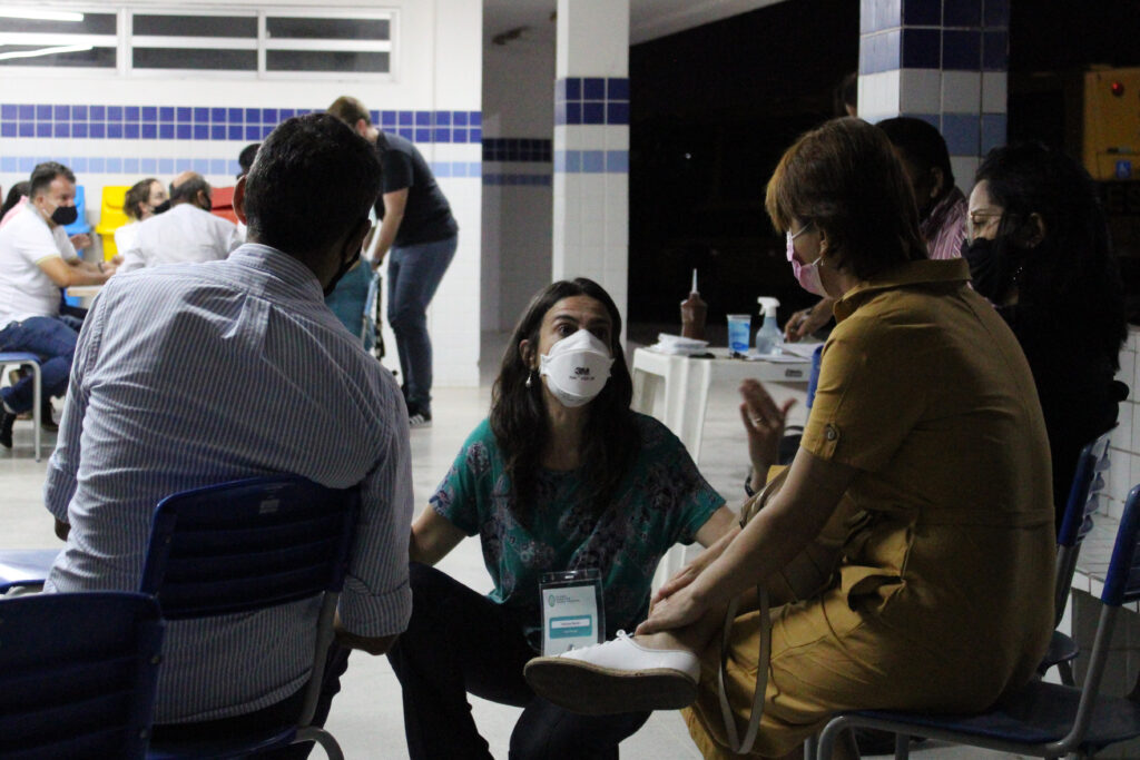 Pessoas sentadas conversando com a facilitadora do evento