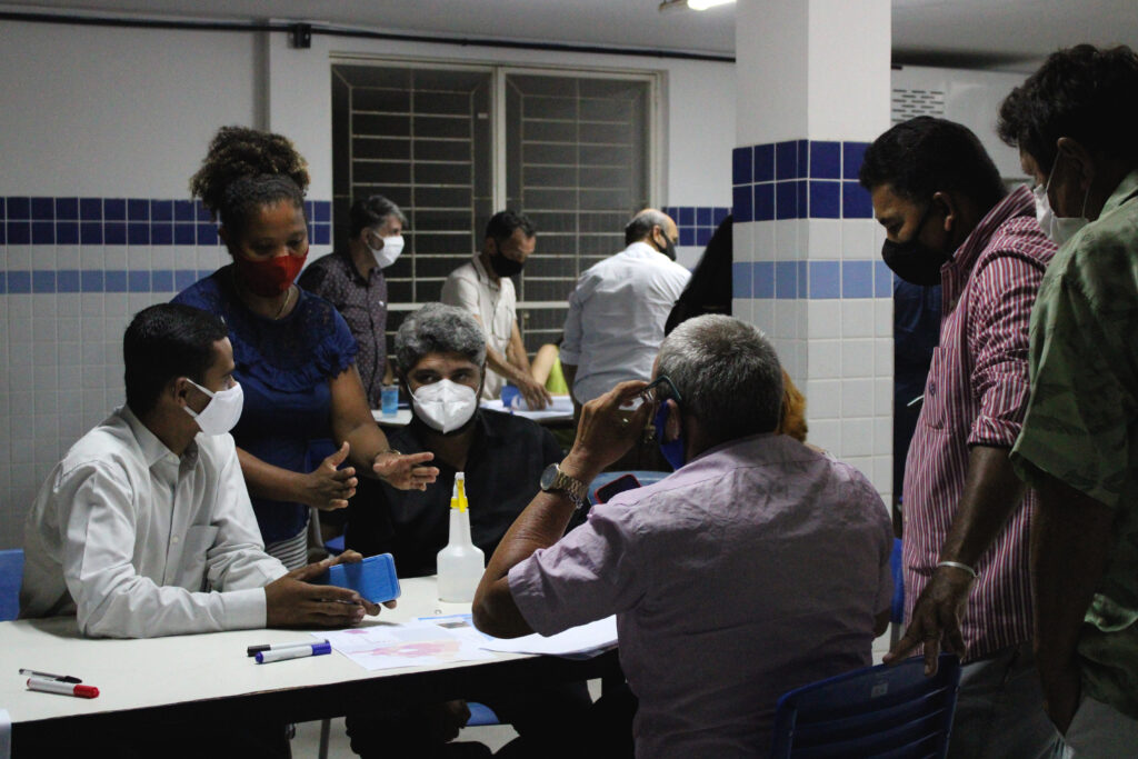 Participantes das oficinas sentados e em pé discutindo propostas