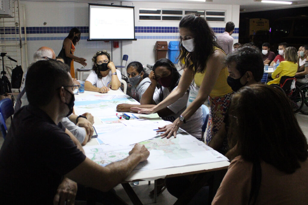 Participantes sentados discutindo e anotando em mapas